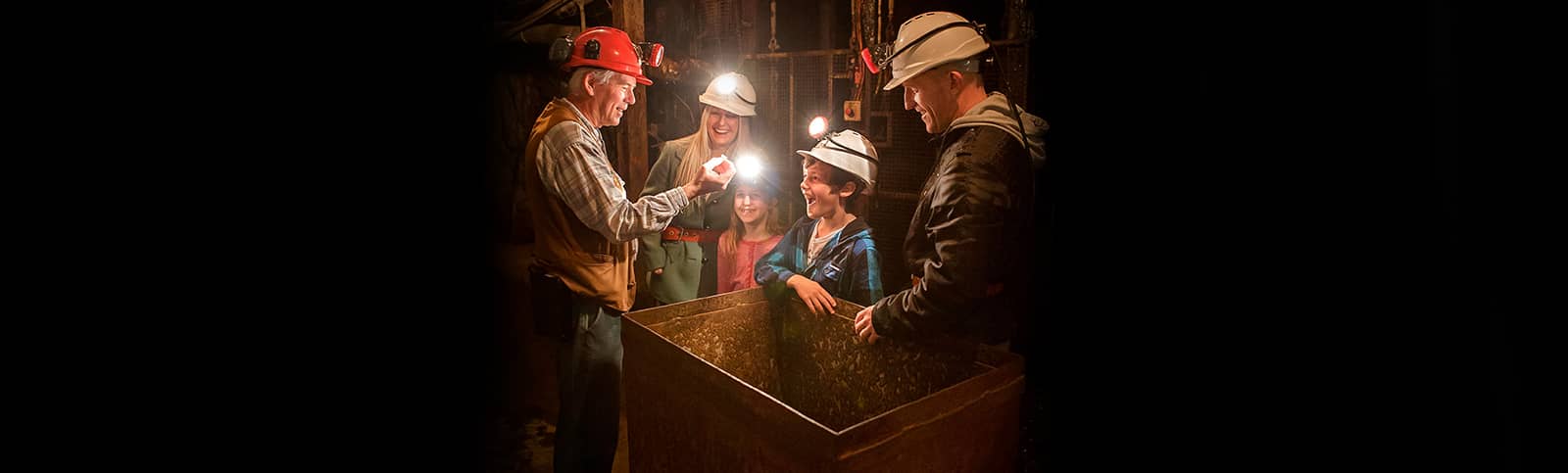 Tour Guide showing family a gold nugget underground on a Mine Experience Tour 