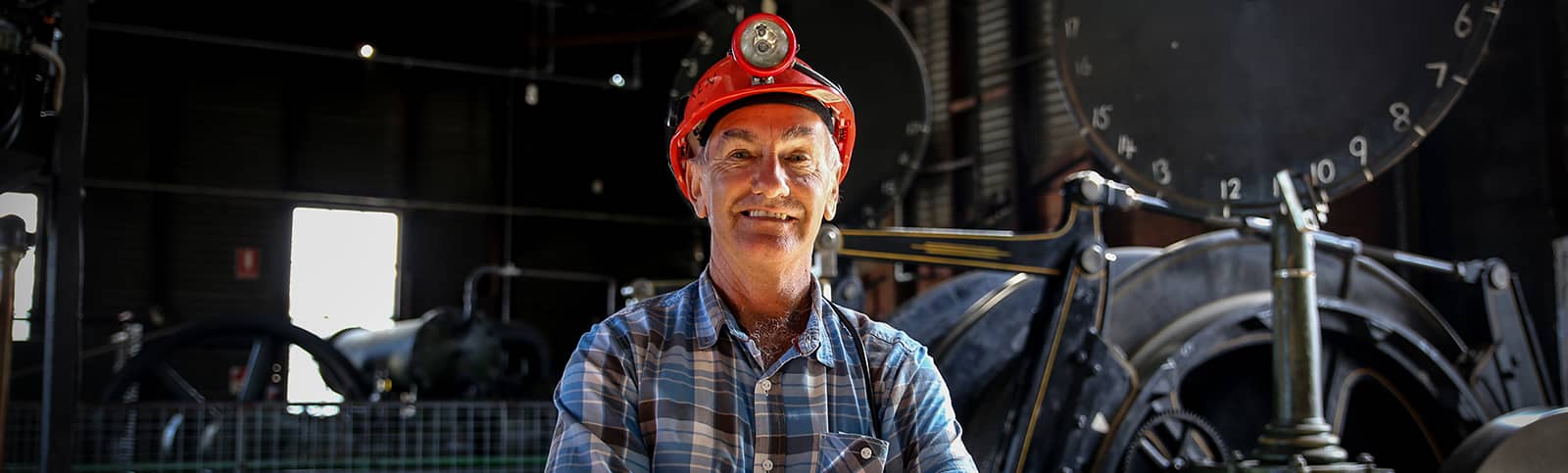 Central Deborah Gold Mine Tour Guide Ken standing in Engine Room with hard hat on