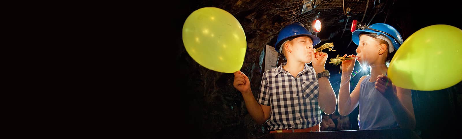 Kids wearing hard hats and holding balloons underground at a Birthday Party