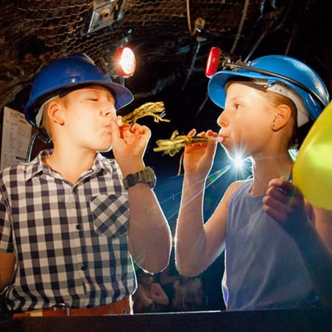 Tour guide showing children gold underground on a Mine Experience